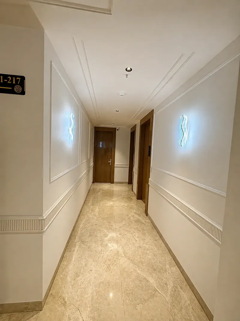 Guest Room Corridor: wood-panelled doors and sculptural wall sconces line each floor. Hotel Silk by Resham, Murthal, Haryana.
